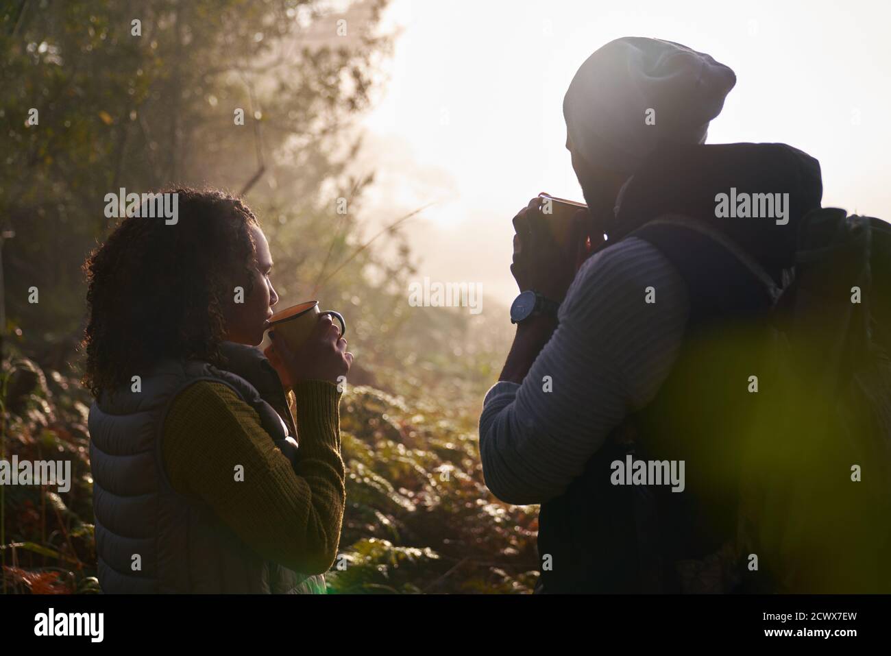 Silueta joven pareja bebiendo café en la naturaleza otoñal Foto de stock
