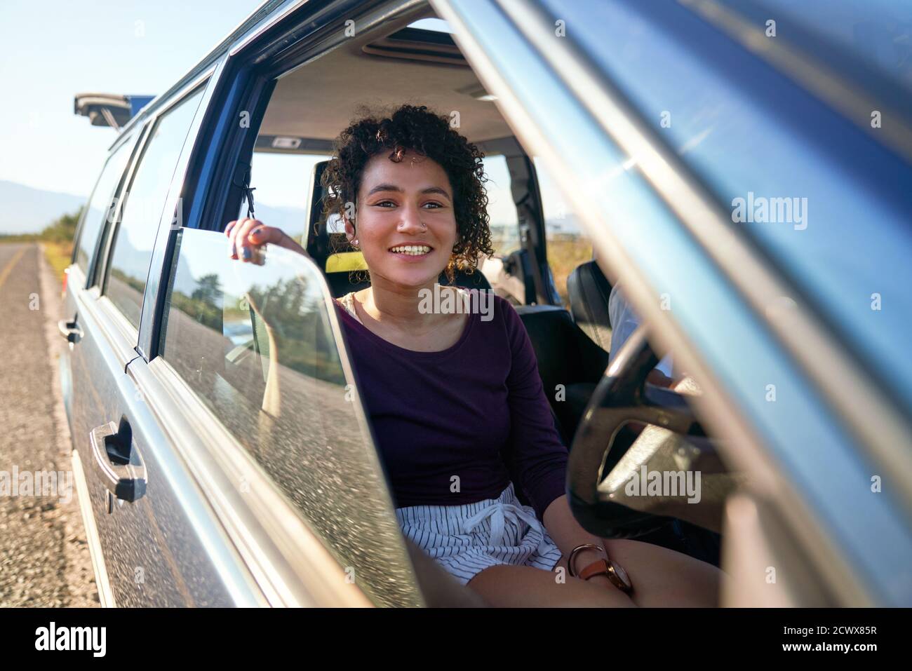 Feliz mujer joven disfrutando de viaje por carretera dentro del coche Foto de stock