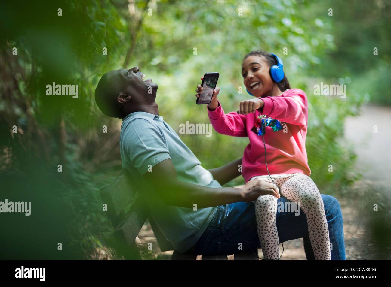 Feliz padre e hija riendo en el banco del parque Foto de stock