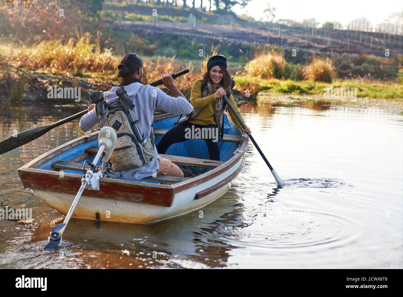 Feliz pareja joven con remos en bote de remos en el soleado otoño lago Foto de stock