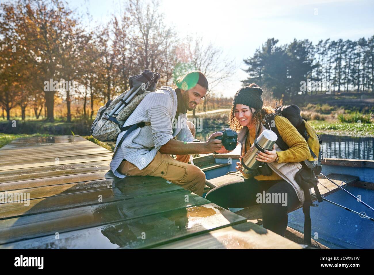 Feliz pareja joven con mochilas usando la cámara en el bote de remos Foto de stock