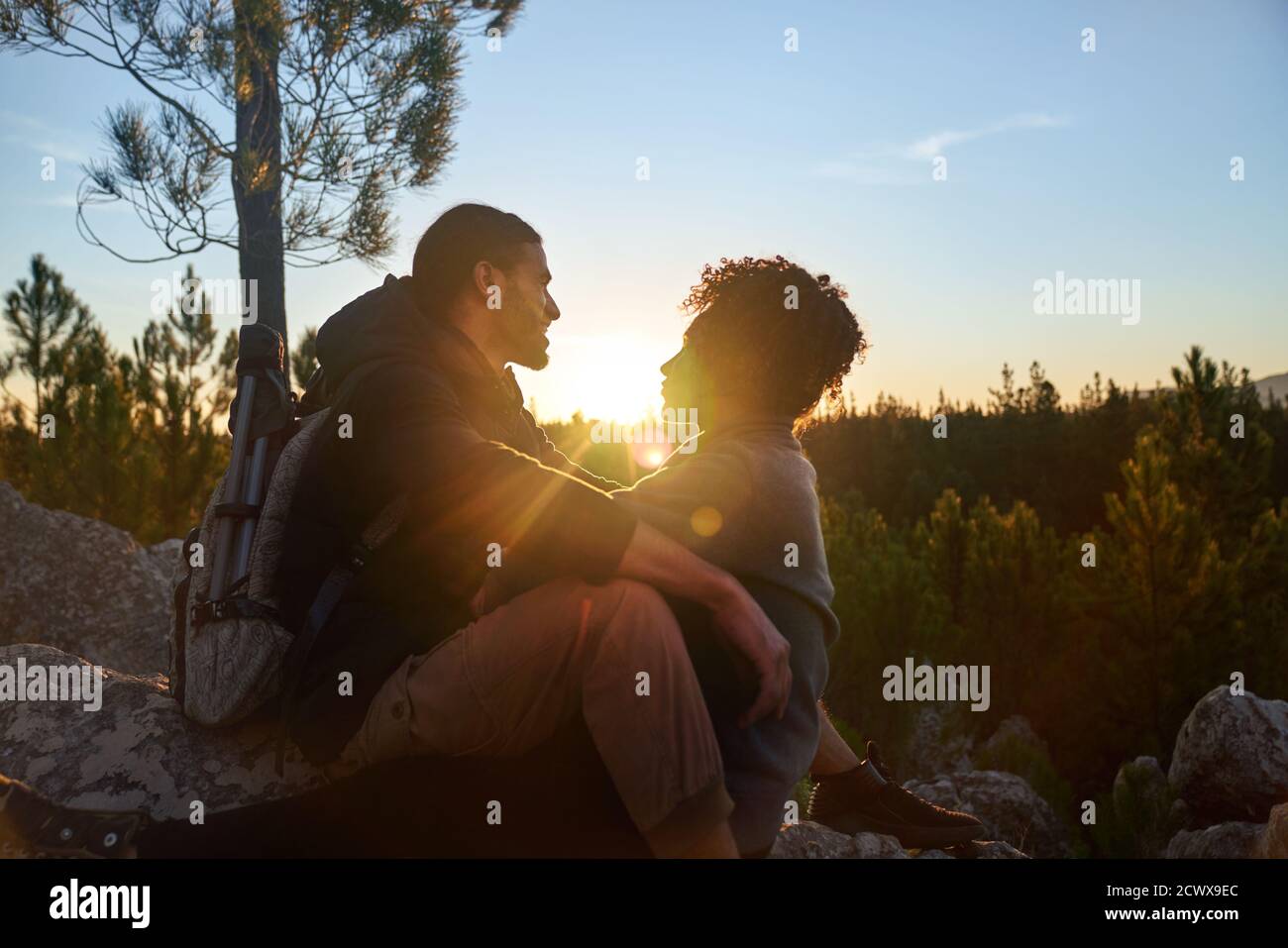 Cariñosa joven pareja de senderismo disfrutando de la tranquila puesta de sol en los bosques Foto de stock