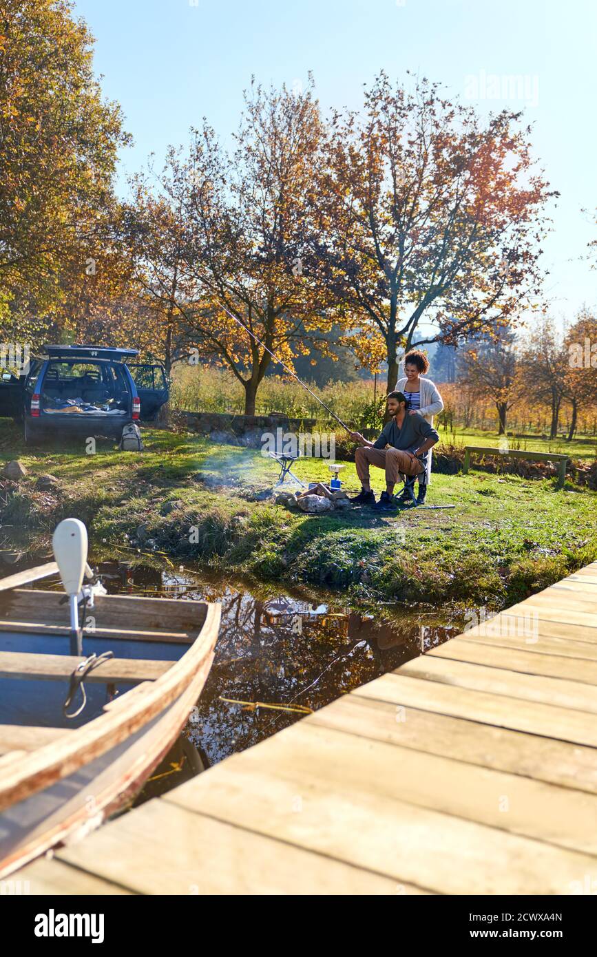 Pareja joven acampando en el soleado otoño junto al lago Foto de stock