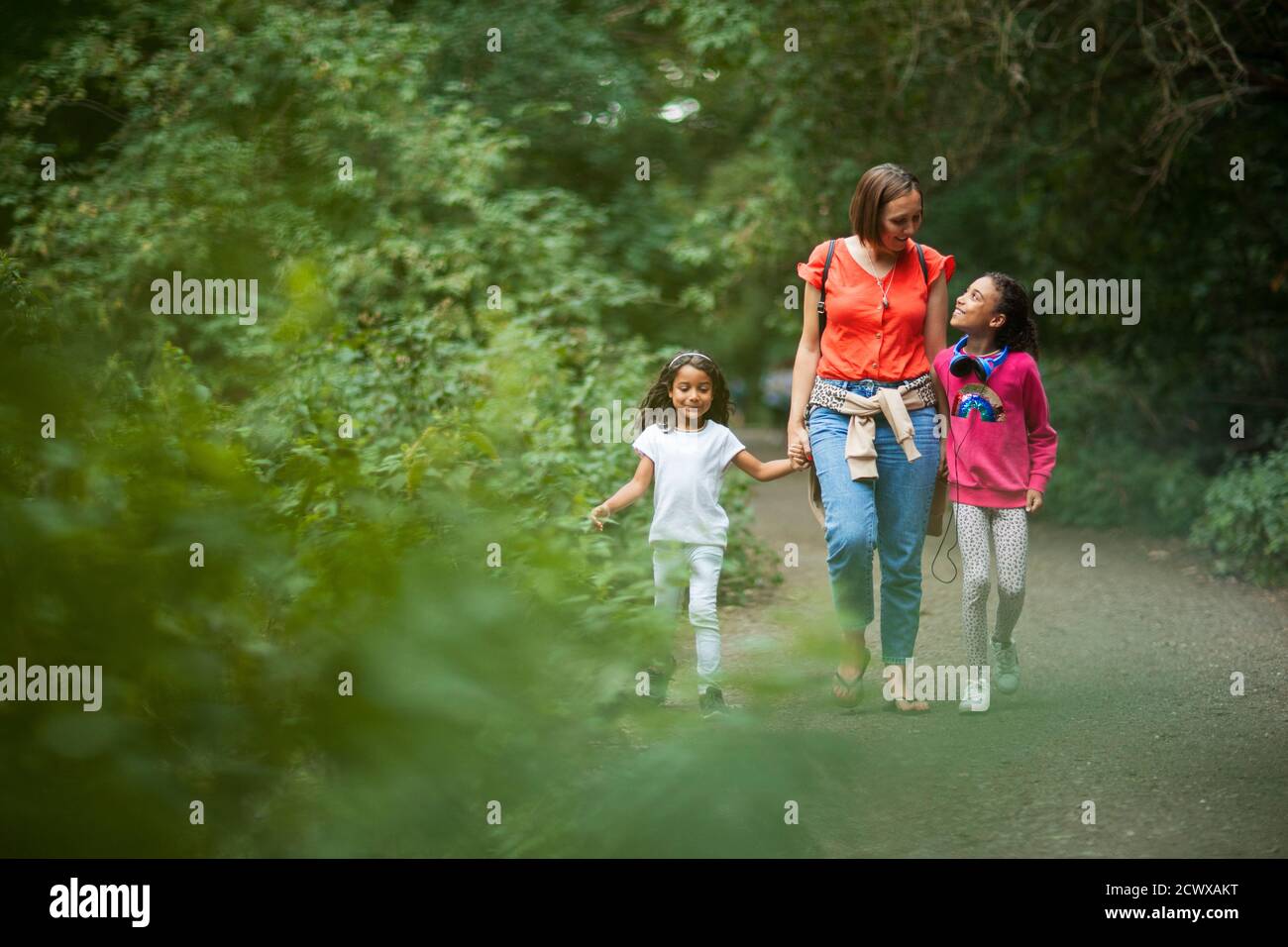 Madre e hijas caminando por el camino en el bosque Foto de stock