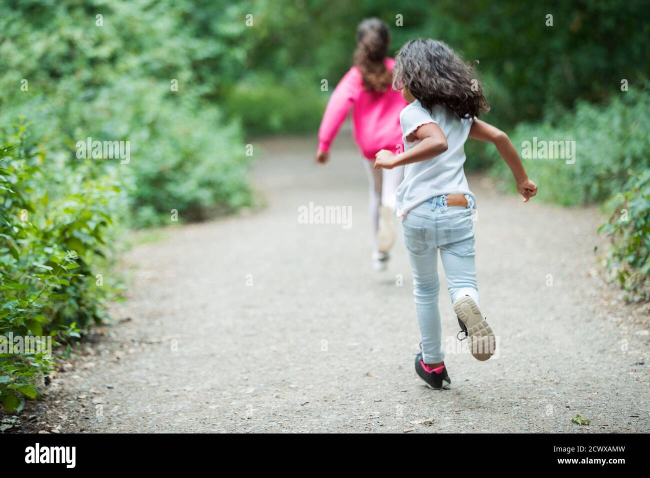 Hermanas despreocupadas corriendo en el camino del parque Foto de stock