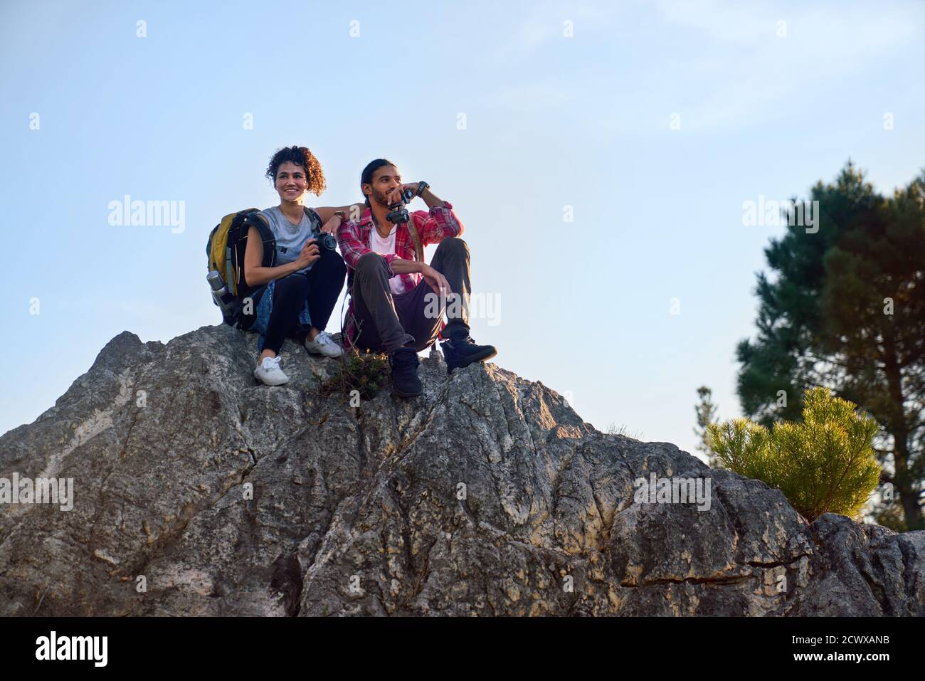 Feliz joven pareja de excursionistas relajándose en el rock Foto de stock