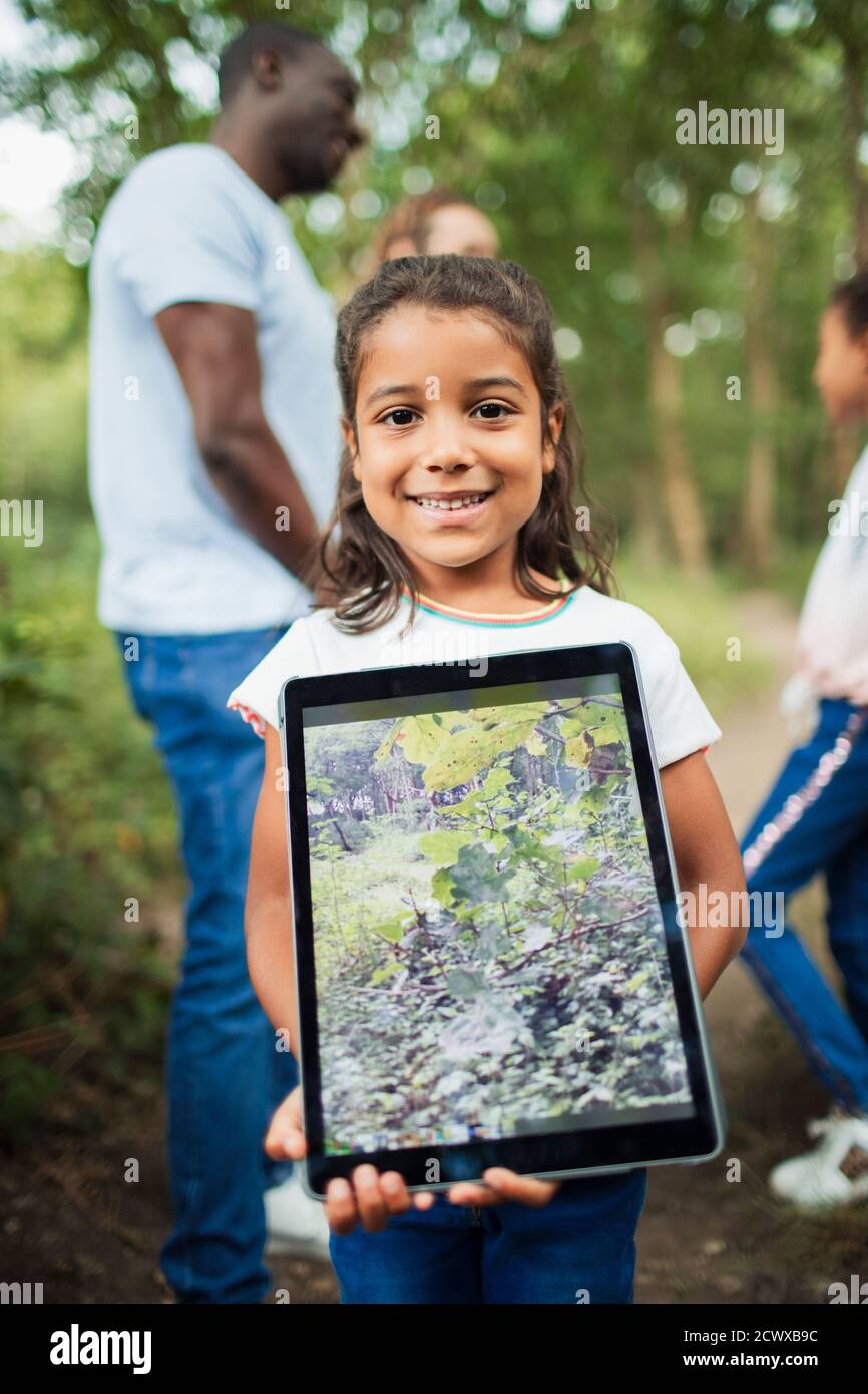 Retrato niña sosteniendo tableta digital con foto de plantas Foto de stock