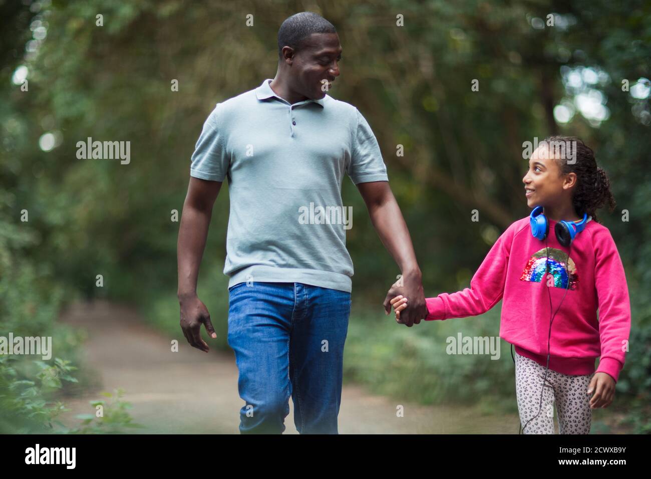Feliz padre e hija con las manos caminando por el camino del parque Foto de stock