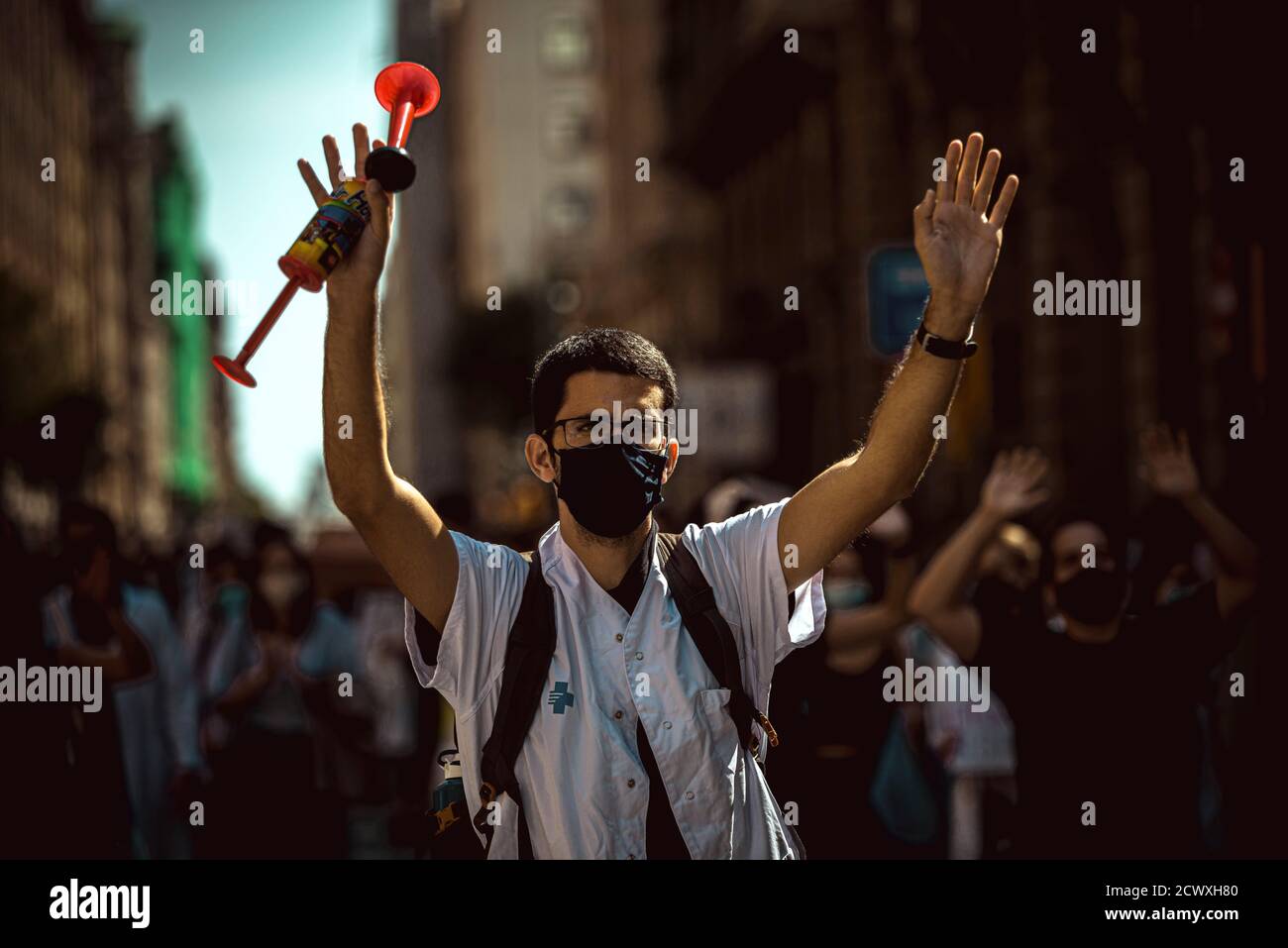 Barcelona, España. 30 de septiembre de 2020. Un joven médico residente  protesta con un cuerno de aire sobre las condiciones precarias durante su  formación de posgrado especializada en el sistema de atención