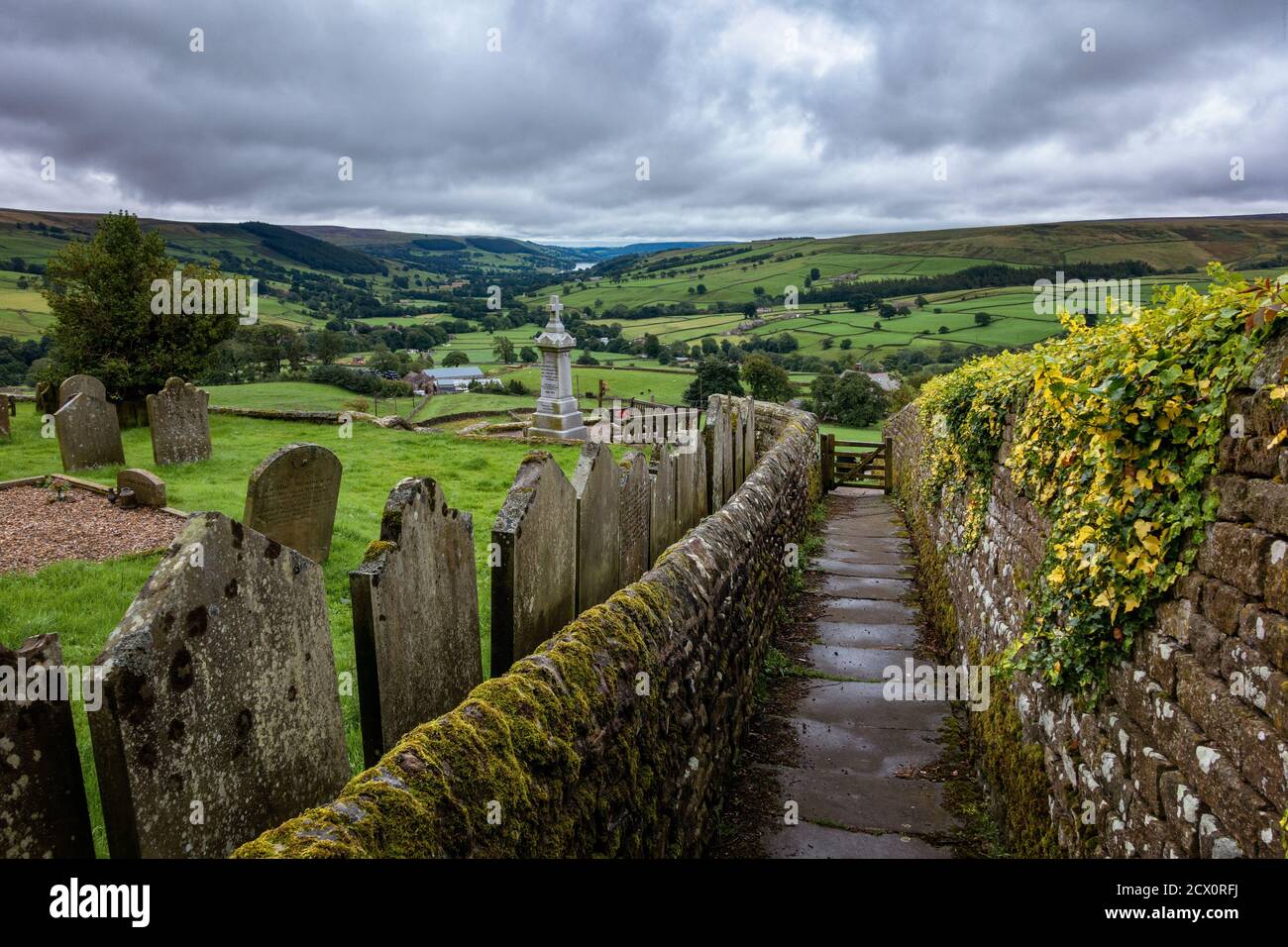 Vea una pared de piedra seca y el camino desde Middlesmoor junto al cementerio a través de Nidderdale hacia Pateley Bridge, North Yorkshire, Reino Unido Foto de stock