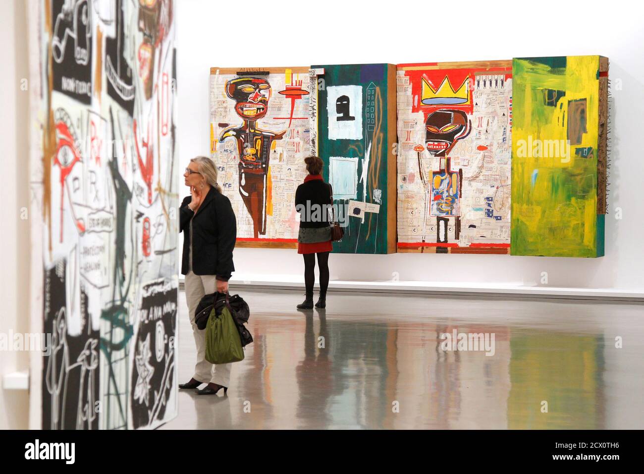 A visitor looks at paintings by U.S. artist Jean-Michel Basquiat  (1960-1988) before the opening of the exhibition "Basquiat" at the Museum  of Modern Art in Paris October 14, 2010. The retrospective exhibition,