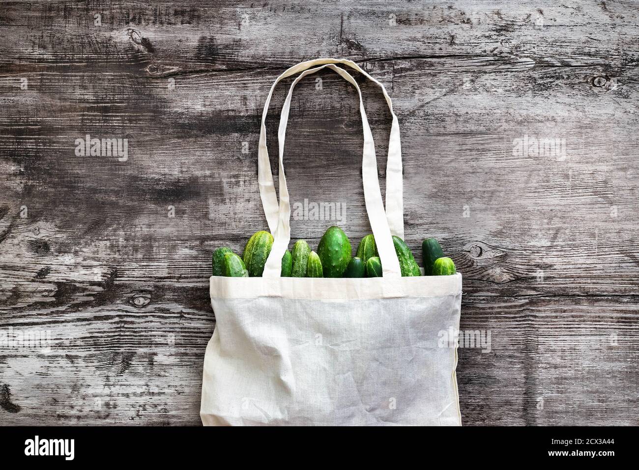 Bolsa tela blanca para mockup plantilla en blanco sobre fondo de madera con vegetables en el interior: Pepinos. Sin residuos. No hay bolsas de plástico. Compras hechas a mano Foto de stock