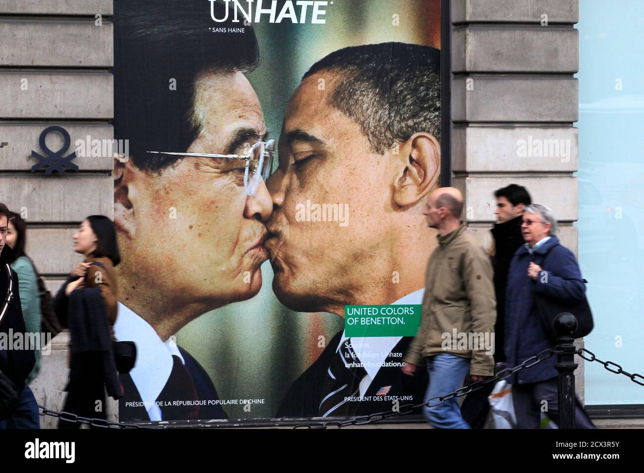 People walk past a billboard showing a photo montage with U.S. President  Barack Obama kissing China's President Hu Jintao displayed on a Benetton  store in Paris November 17, 2011. Photo montages of