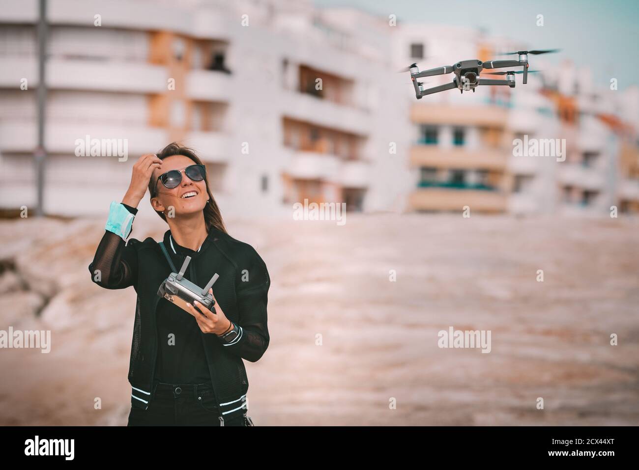 Bonita y moderna mujer piloto sonriente con ropa oscura y elegante controla  el drone con mando a distancia. Pasatiempo al aire libre Fotografía de  stock - Alamy