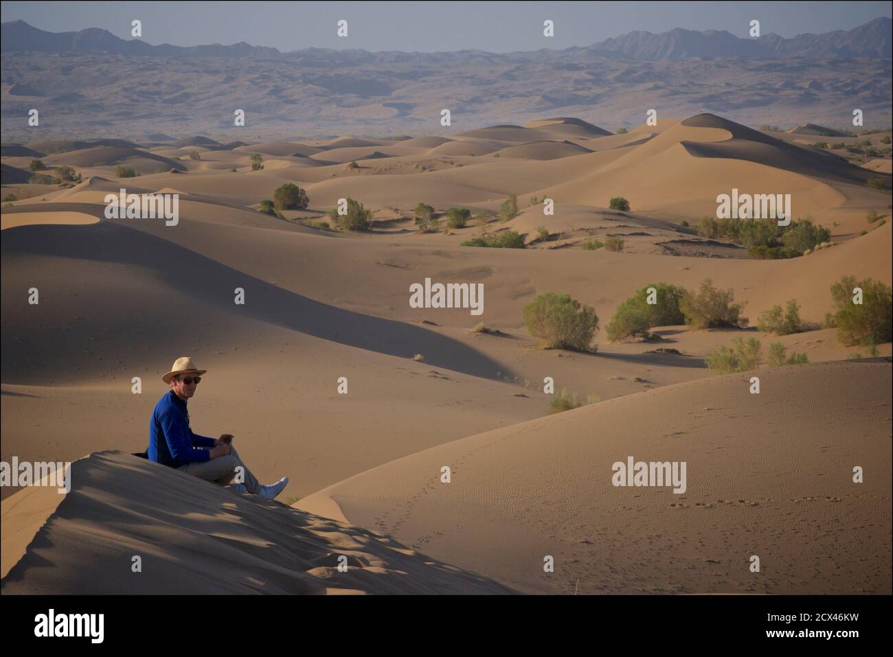 Viajero occidental sentado en las dunas de arena de Mesr, cerca de Khur en el centro de Irán. El desierto de Kavir. Dasht-e Kavir. Modelo emitido. Foto de stock