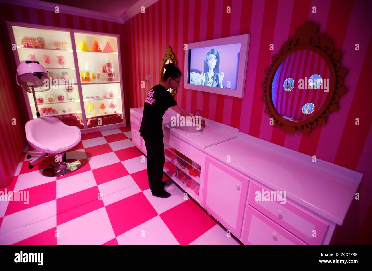 A staff poses for the photographer inside a life-size "Barbie Dreamhouse"  of Mattel's barbie dolls in the bathroom during a media tour in Berlin, May  15, 2013. The life-sized house, covering about
