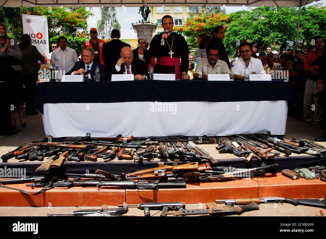Army chaplain Fabio Colindres (C) speaks next to Jose Miguel Insulza (2nd  L), secretary general of the Organization of American States (OAS), in  front of weapons handed over by gang members as