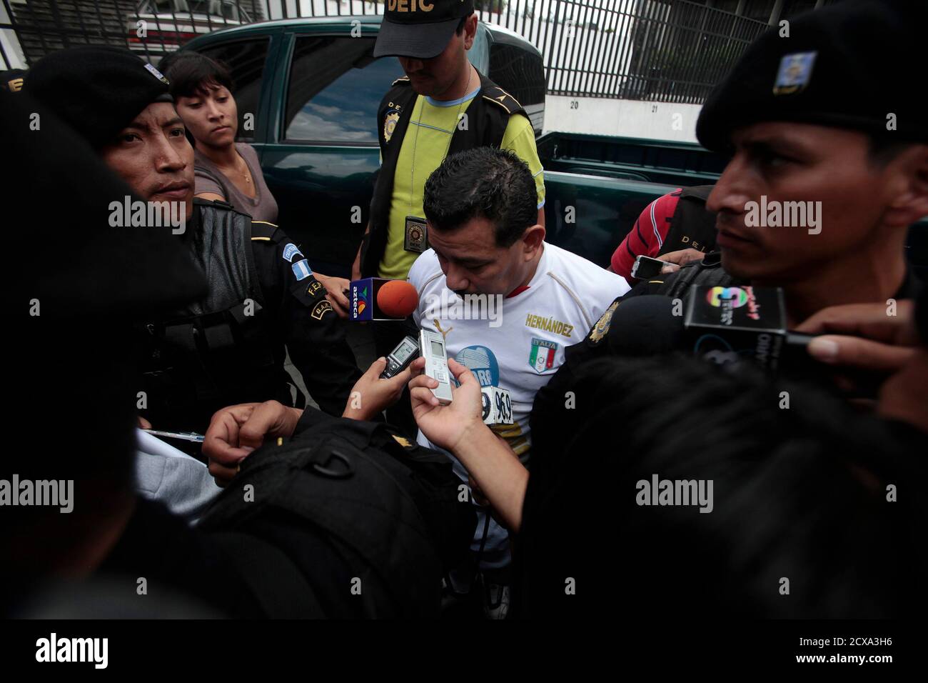 Police escort Juan Hernandez Sanchez (C), a suspect in the murder of Argentine folk singer Facundo Cabral, in Guatemala City July 31, 2011. Cabral was killed on July 9, 2011 while on the way to the airport in Guatemala City when gunmen opened fire on the car he was in as part of a plot by organized crime gangs to kill his music promoter Henry Farina. Farina, who was driving the car at the time of the shooting, was badly injured. Hernandez Sanchez, 45, is the third man to be detained in connection with the case when he was arrested on Sunday in Aldea Aceituno in the Escuintla region while in th Foto de stock