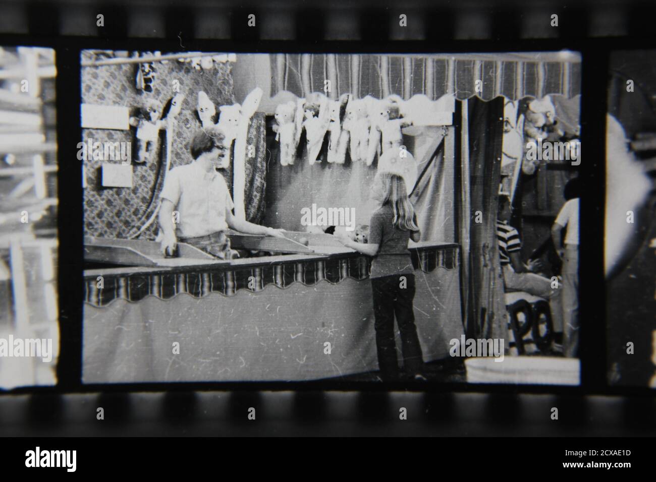 Fotografía en blanco y negro de la cosecha de los años 70 de un tipo regular que manning un puesto de juego del carnaval en una feria de la calle del carnaval. Foto de stock