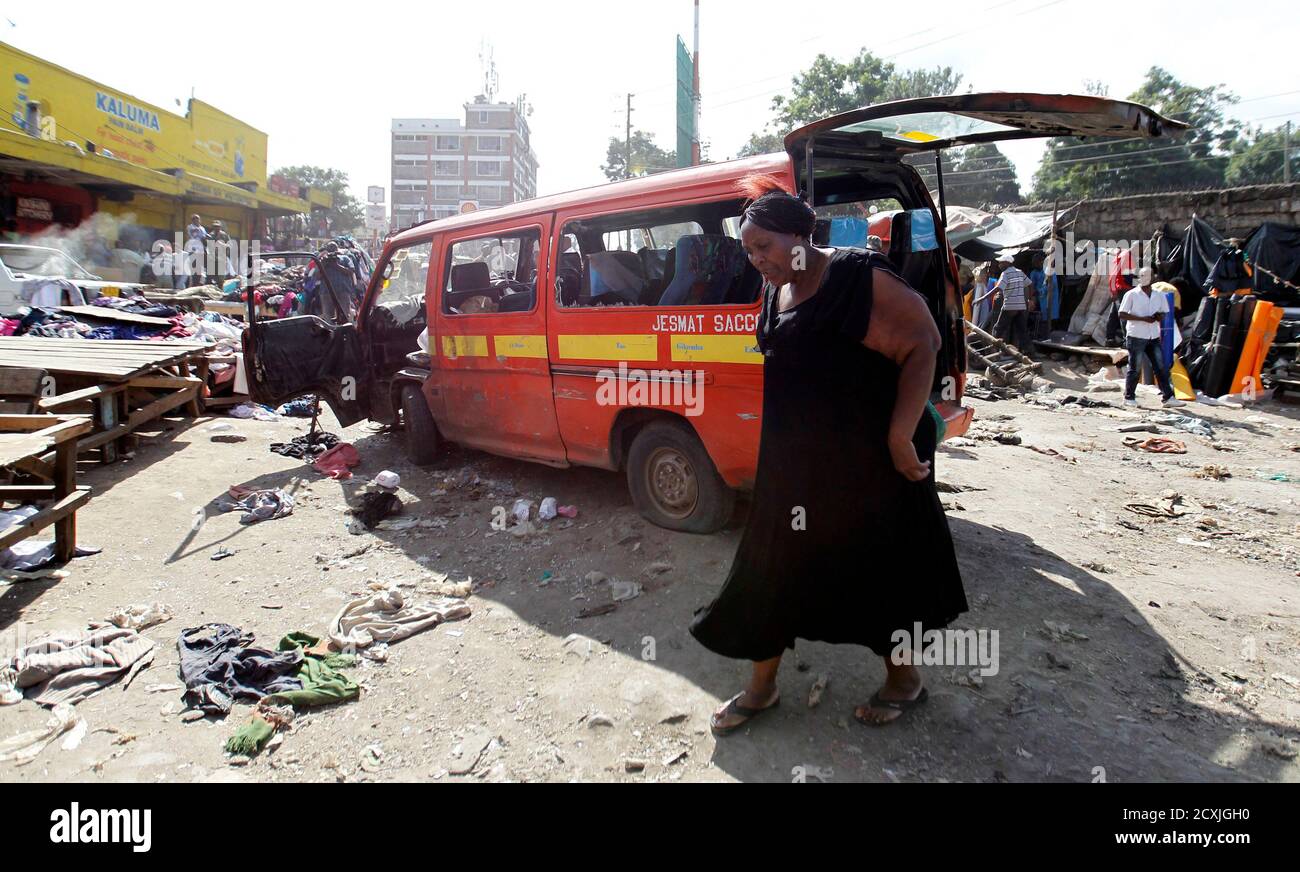 Una mujer camina cerca de un vehículo dañado en la escena de una explosión gemela en el mercado al aire libre de Gikomba para ropa de segunda mano en la capital de Kenia, Nairobi, 16 de mayo de 2014. Al menos cuatro personas murieron el viernes en dos explosiones en Nairobi, dijo el Centro Nacional de Operaciones de Desastres (NDOC) del país. REUTERS/THOMAS MUKOYA (KENIA - TAGS: DISTURBIOS CIVILES LEY DE DELINCUENCIA TPX IMÁGENES DEL DÍA) Foto de stock
