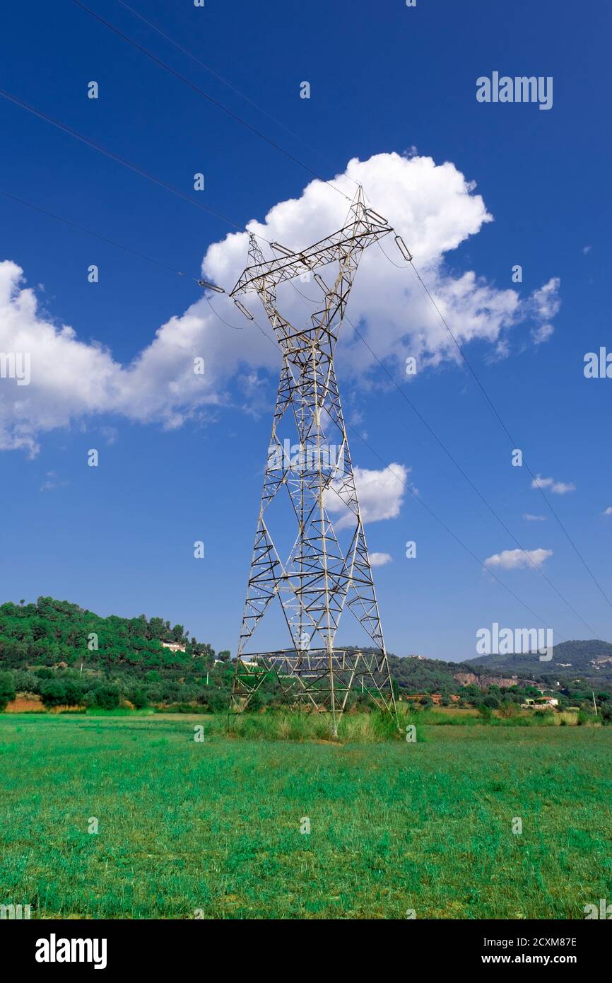 Torre eléctrica contra un cielo azul y algunas nubes blancas en un campo. Concepto de energía limpia y espacio de copia vacío para el texto del editor. Foto de stock