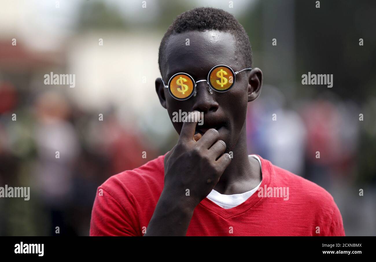 Un niño lleva gafas de sol con el signo del dólar mientras camina por una calle en Bujumbura, Burundi 29 de abril de 2015. REUTERS/Thomas Mukoya IMÁGENES TPX DEL DÍA Foto de stock
