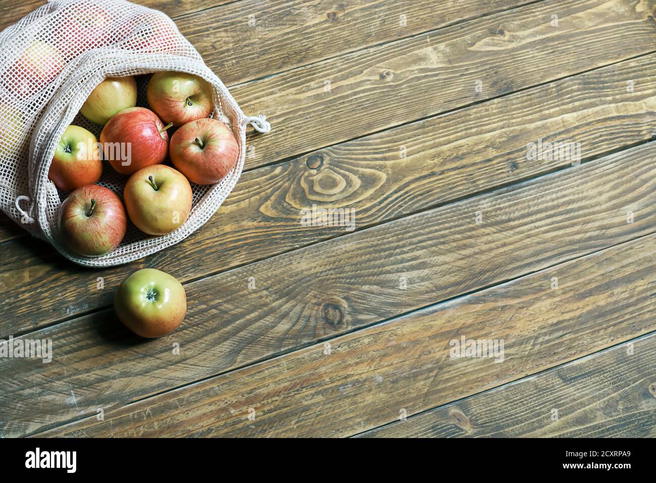 Manzanas orgánicas en bolsa de tela de malla reutilizable ecológica sobre fondo de madera. Concepto de cero residuos, estilo de vida libre de plástico. Vista superior, espacio de copia Foto de stock
