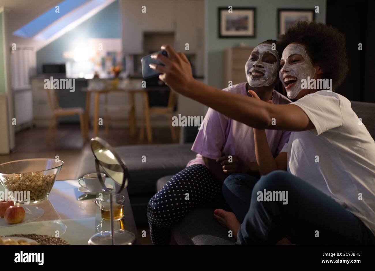 Mujeres felices y diversas en máscaras cosméticas tomando selfie durante el sueño fiesta Foto de stock