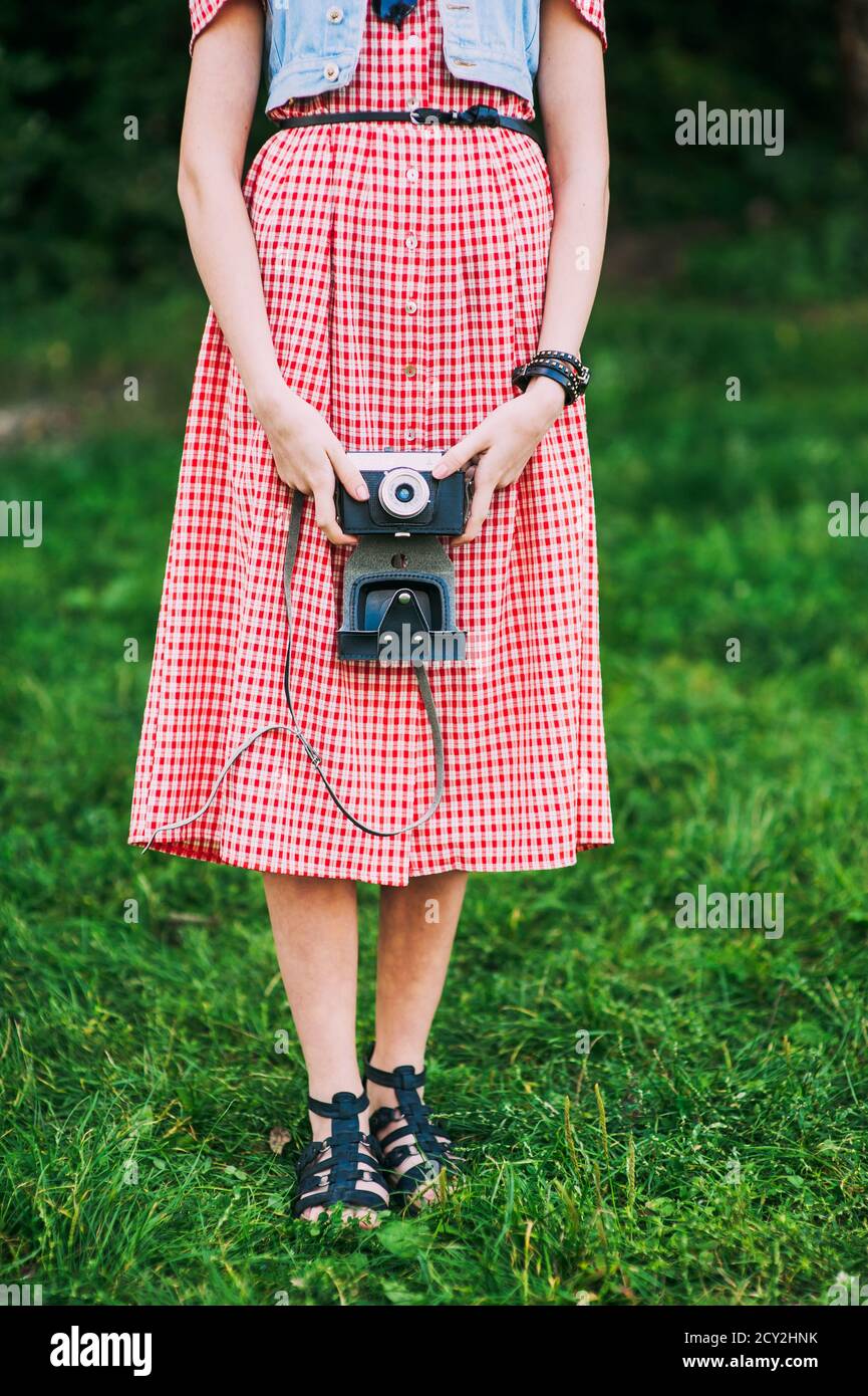 Niña rostro con retro sostiene una cámara vintage sobre fondo de hierba verde Fotografía de stock -