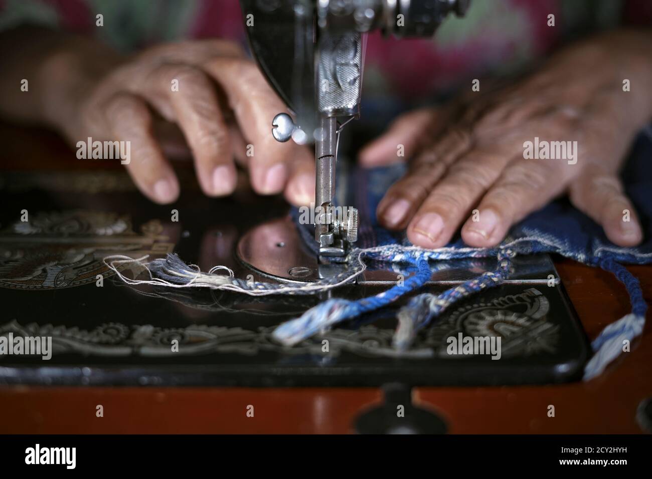 Manos de la mujer de cerca trabajando en la alfombra de oración tradicional con vieja máquina de coser Foto de stock