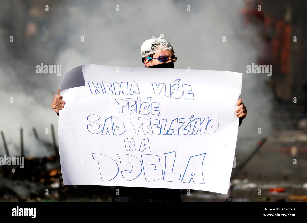 An anti-government protester holds a placard, which reads: "No more talking, now I take action", in front of a government building in Tuzla February 7, 2014. Protesters across Bosnia set fire to government buildings and fought with riot police on Friday as long-simmering anger over lack of jobs and political inertia fuelled a third day of the worst civil unrest in Bosnia since a 1992-95 war. REUTERS/Dado Ruvic (BOSNIA AND HERZEGOVINA - Tags: POLITICS CIVIL UNREST) Foto de stock