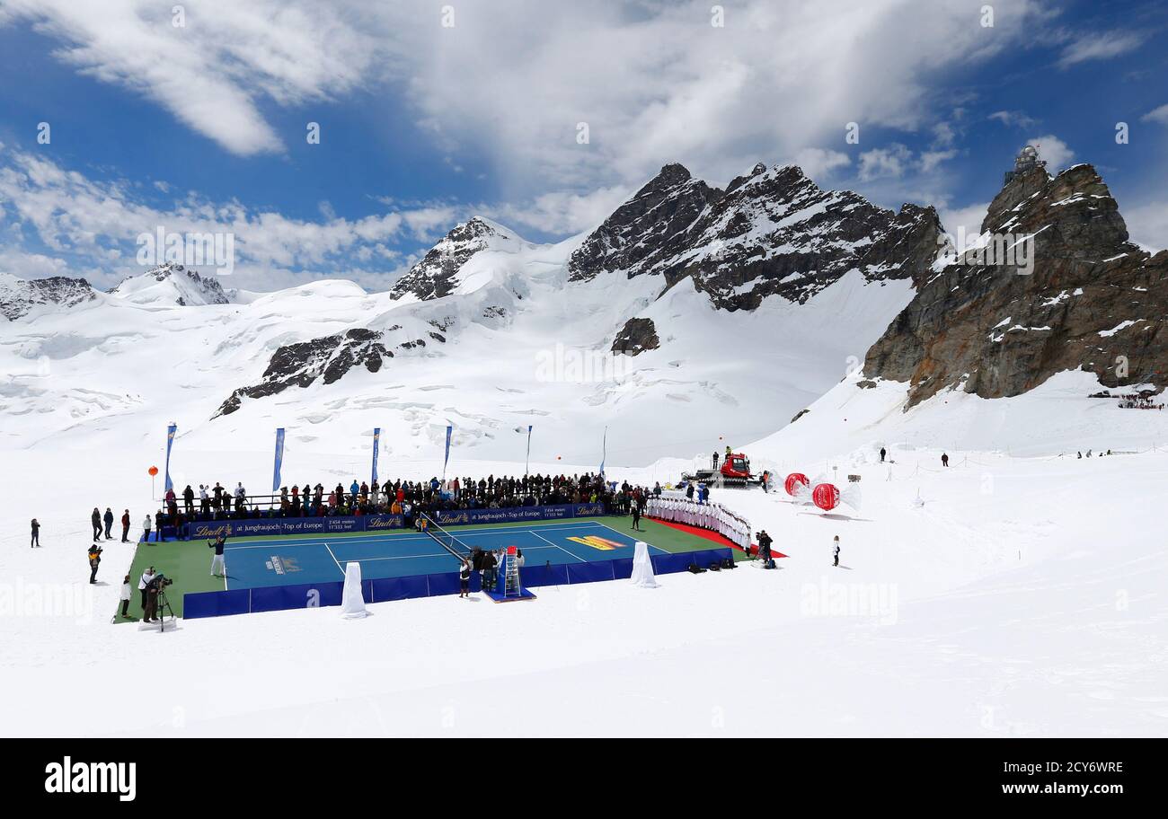 El tenista suizo Roger Federer (L) sirve una pelota al esquiador estadounidense Lindsey Vonn durante un evento promocional de tenis en el glaciar Aletsch en el Jungfraujoch el 16 de julio de 2014. El número tres del mundo y el campeón de esquí alpino jugaron en una pista de tenis especialmente preparada en un glaciar a una altitud de 3475 m (11401 pies). REUTERS/DENIS BALIBOUSE (SUIZA - TAGS: SOCIEDAD DEPORTE TENIS ESQUÍ TPX IMÁGENES DEL DÍA) Foto de stock