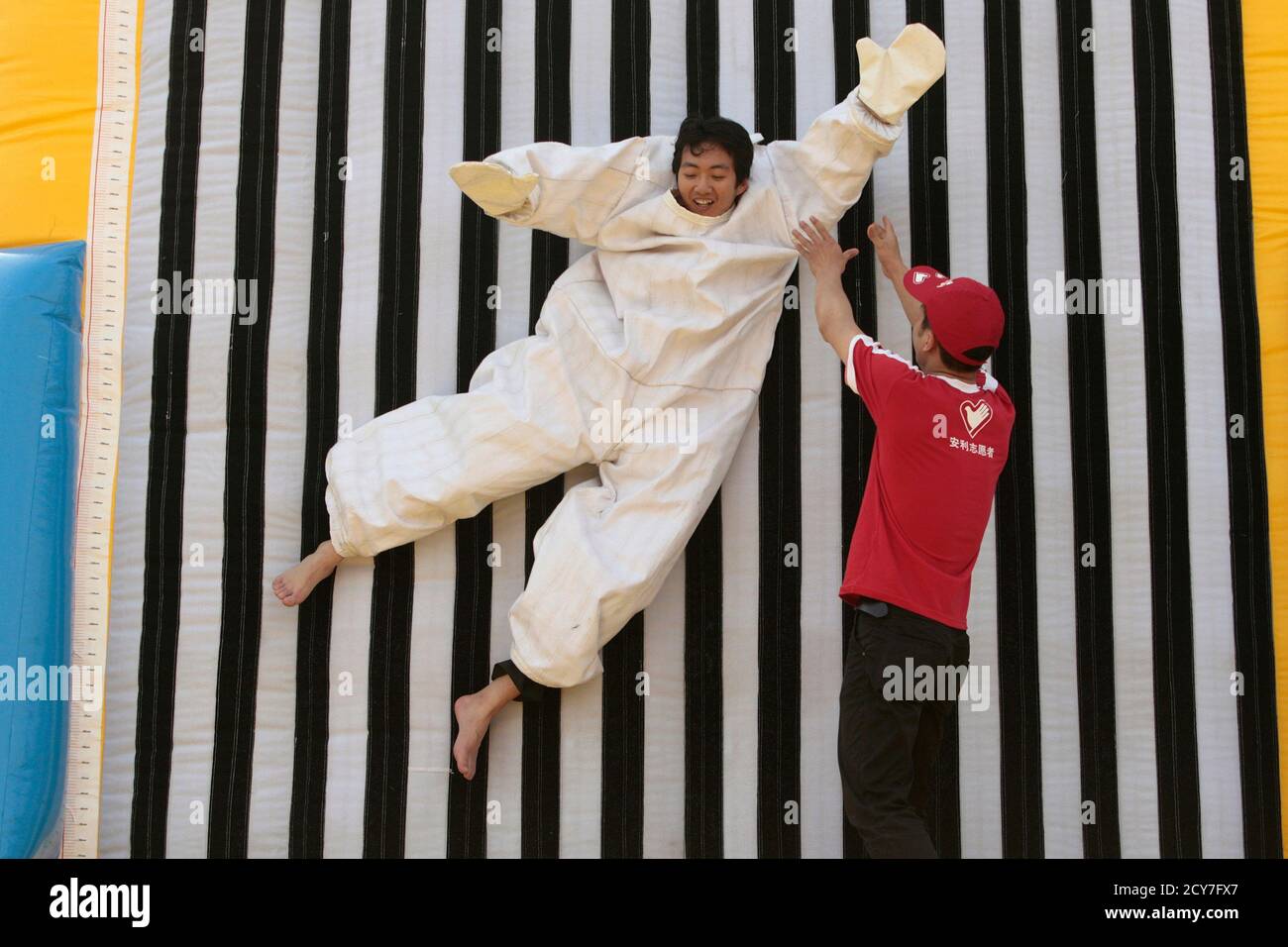 A visitor wearing a velcro suit sticks himself to an air-filled wall at a  park in Nanjing, Jiangsu province May 1, 2011. The game was held for  visitors as part of the