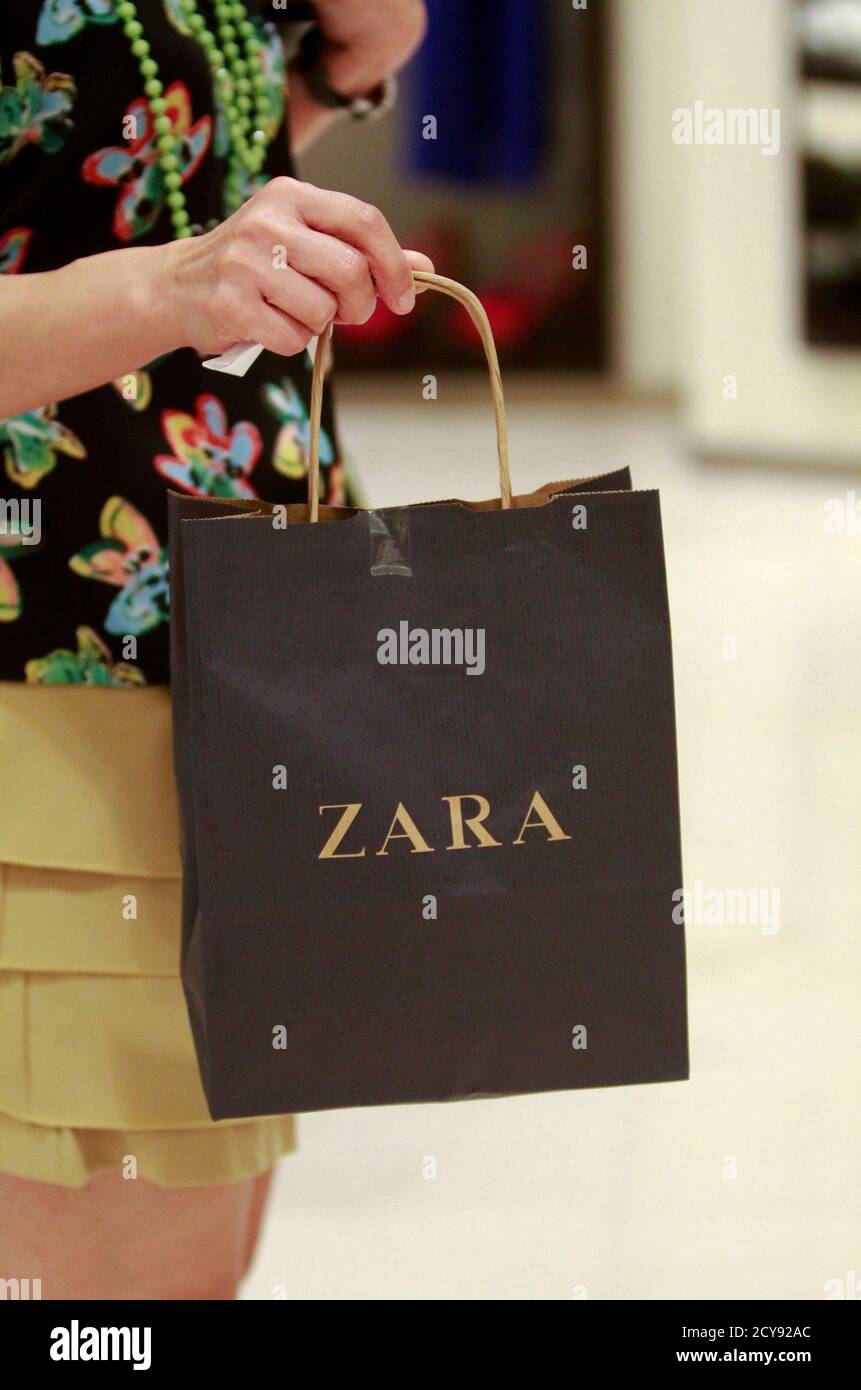 Una mujer tiene una bolsa de compras en una tienda Zara en el centro  comercial Siam Paragon en Bangkok 29 de junio de 2011. Mientras la música  pop se sonaba desde una
