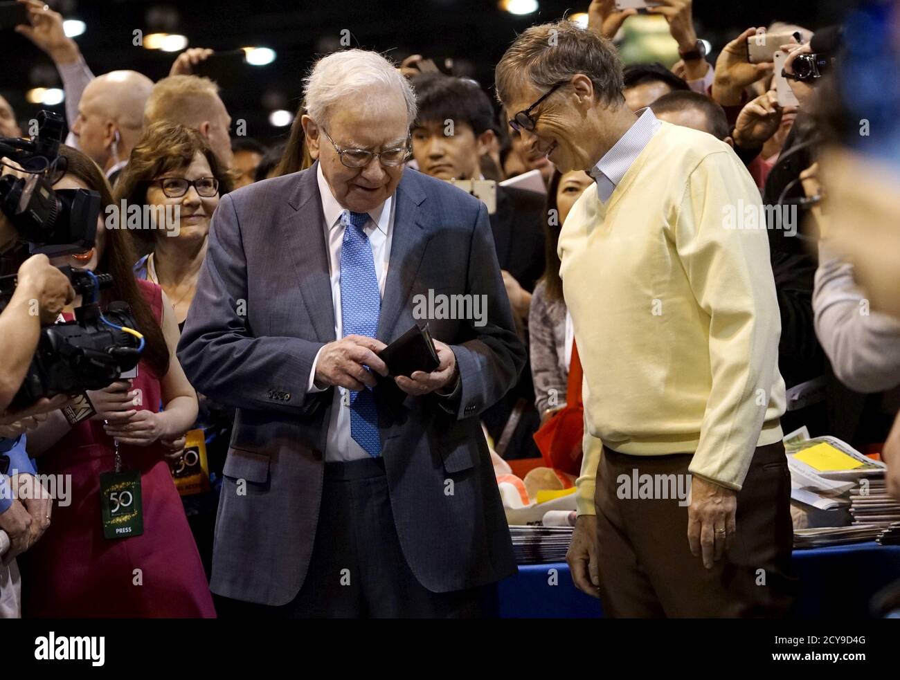 Warren Buffett (L), CEO de Berkshire Hathaway, obtiene su cartera para pagar una apuesta al co-fundador de Microsoft Bill Gates después de participar en un concurso de lanzamiento de periódicos antes de la reunión anual de Berkshire en Omaha, Nebraska, 2 de mayo de 2015. REUTERS/Rick Wilking Foto de stock