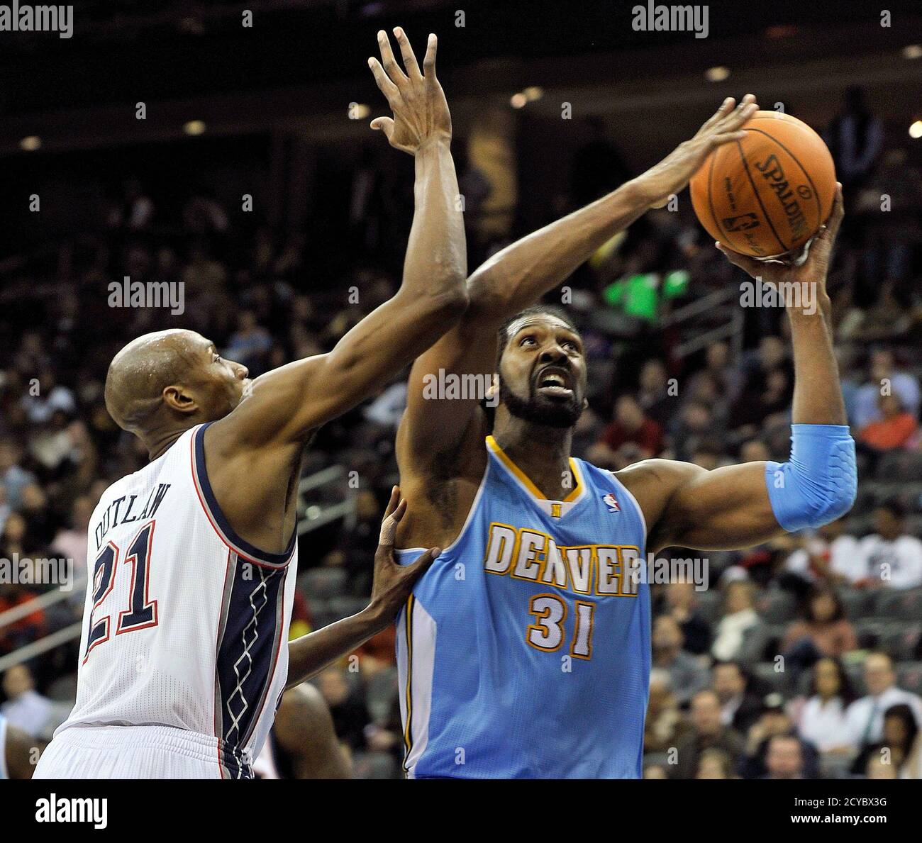 Denver Nuggets center Nene Hilario grabs a rebound over New Jersey Nets  forward Travis Outlaw (L) in the first quarter of their NBA basketball game  in Newark, New Jersey, January 31, 2011.