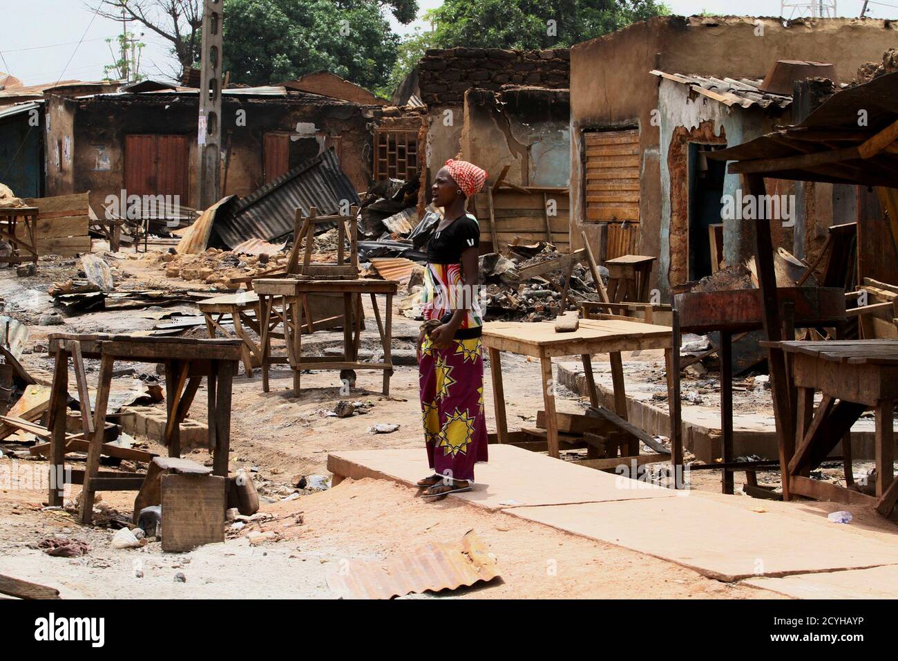 A woman stands in front of burnt buildings in Kachia village, where violence erupted last week, in Nigeria's northern state of Kaduna April 28, 2011. Voters trickled out to polling stations on Thursday in two states in northern Nigeria where rioting killed hundreds last week, under the watchful eye of policemen on horseback and soldiers manning barricades. REUTERS/Afolabi Sotunde (NIGERIA - Tags: CIVIL UNREST ELECTIONS POLITICS) Foto de stock
