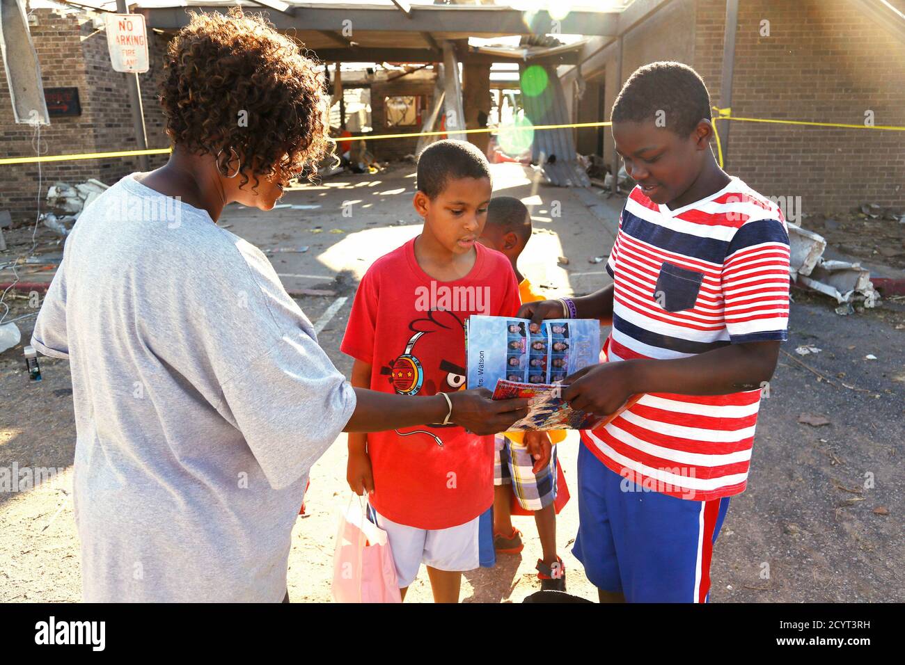 Jordan Humphrey (R), 6th grader at tornado-damaged Briarwood elementary  school, shows his mother Mary (L) and his 3rd grader brother Jacob his  soggy yearbook after his backpack was retrieved for him by