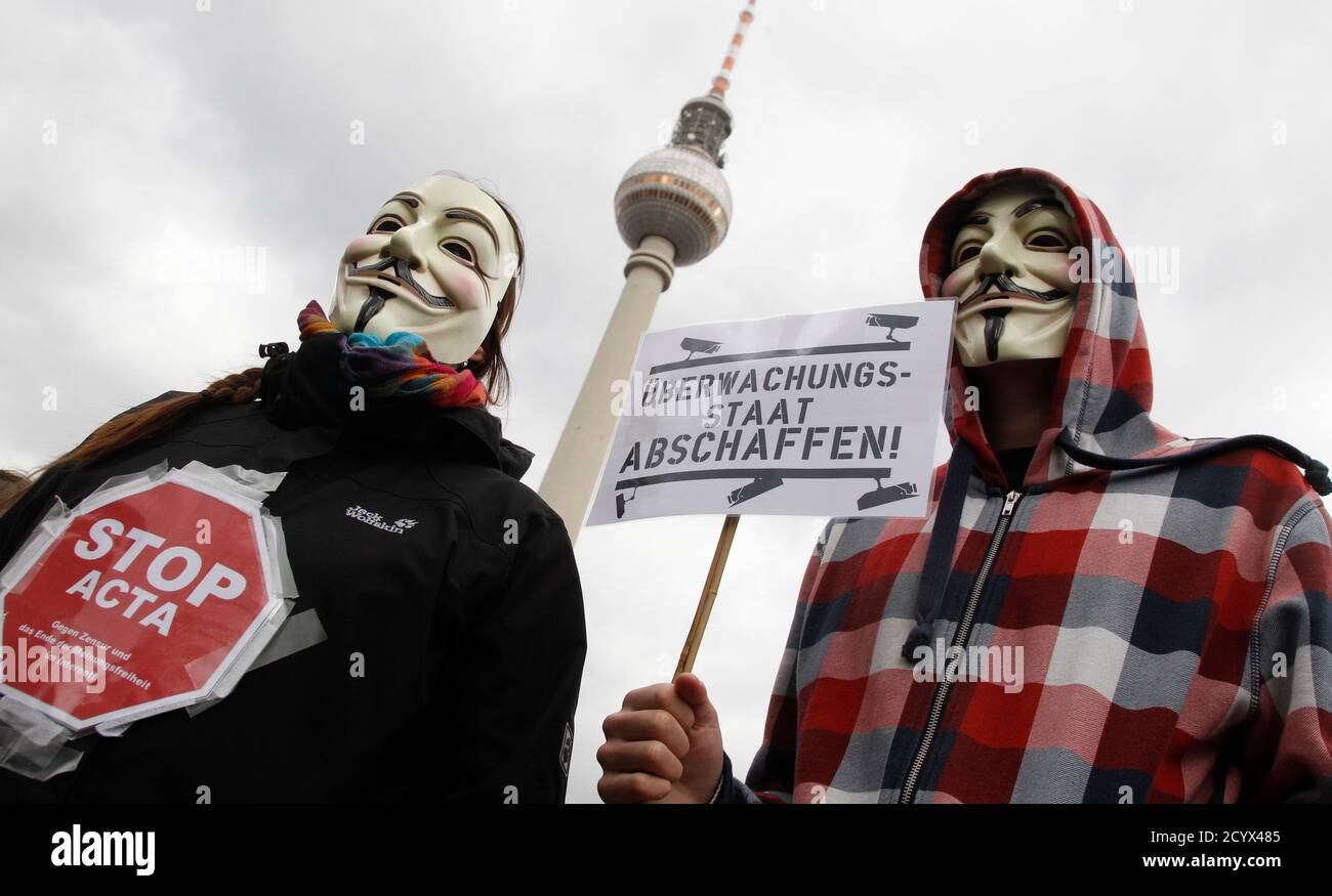 Protestors wearing Guy Fawkes masks participate in a demonstration next to the television tower against the Anti-Counterfeiting Trade Agreement (ACTA) in Berlin February 25, 2012. Protesters fear that ACTA, which aims to cut trademark theft and other online piracy, will curtail freedom of expression, curb their freedom to download movies and music for free and encourage Internet surveillance. The banner reads: 'Surveillance Society.' REUTERS/Tobias Schwarz (GERMANY - Tags: POLITICS) Foto de stock