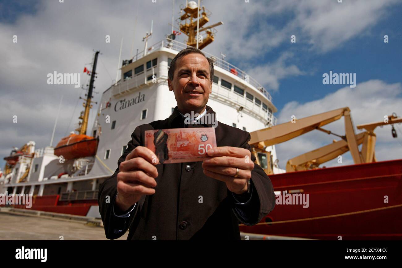 El gobernador del Banco de Canadá, Mark Carney, tiene el nuevo billete canadiense de 50 dólares, hecho de polímero, frente al CCGS Amundsen, el buque de investigación del Ártico representado en el reverso del nuevo proyecto de ley, en la ciudad de Quebec, 26 de marzo de 2012. REUTERS/Mathieu Belanger (CANADÁ - Tags: NEGOCIOS) Foto de stock