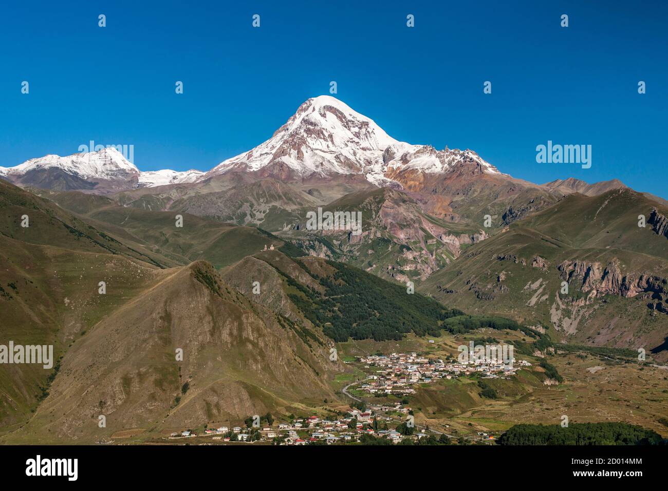 Monte Kazbek (5047m), el pueblo de Gergeti y Trinidad Gergeti Iglesia en las montañas del Cáucaso del norte de Georgia. Foto de stock