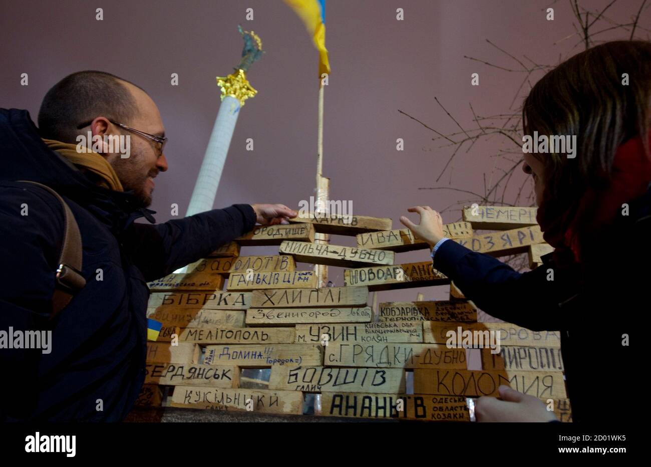 Igor Skliarevsky and his wife Elena place a wooden block displaying the name of Ukrainian city Kharkiv where they met, as pro-European integration protesters erected a symbolic wall using the blocks during a rally in Independence Square in central Kiev, December 16, 2013. By day, Igor Skliarevsky works as a graphic designer. By night, he is an anti-government protester, sometimes manning the barricades in Ukraine's snowy capital. The 36-year-old delivers maps for fellow protesters, directing them to medical posts or kitchens. He also set up a website coordinating food, warm clothing and other Foto de stock
