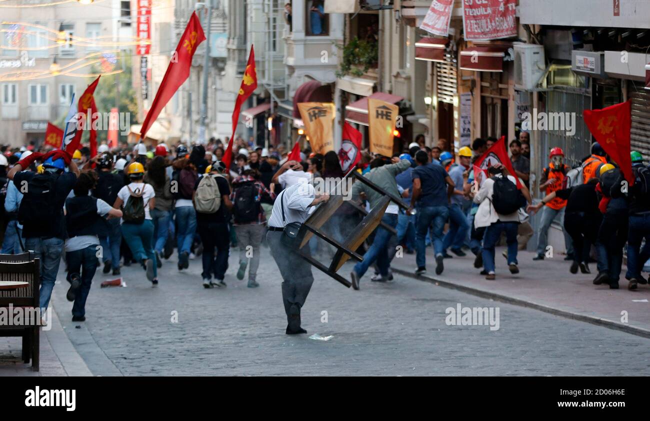 Demonstrators run for cover as riot police use tear gas to disperse them during a protest in central Istanbul September 10, 2013. Turkish police fired rounds of teargas to disperse a crowd of several hundred demonstrators rallying in central Istanbul on Tuesday against the death of a protester in the southern province of Hatay earlier in the day, witnesses said. Dozens of riot police backed by water cannon advanced down a main pedestrian avenue and some fired teargas canisters into side streets as protesters fled after the police blocked their entrance into the city's Taksim Square. As the pol Foto de stock