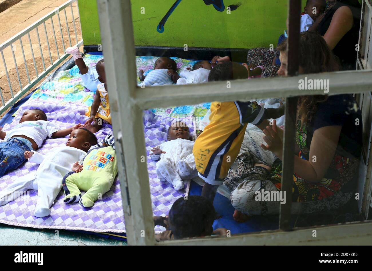 Voluntarios extranjeros juegan con niños abandonados en una casa en la capital de Uganda, Kampala, 14 de mayo de 2015. Las familias ugandesas han sido sobornadas, engañadas o coaccionadas para entregar a sus hijos a ciudadanos estadounidenses y otros extranjeros para su adopción, según una investigación de la Fundación Thomson Reuters. Foto tomada el 14 de mayo de 2015. REUTERS/James Akena Foto de stock