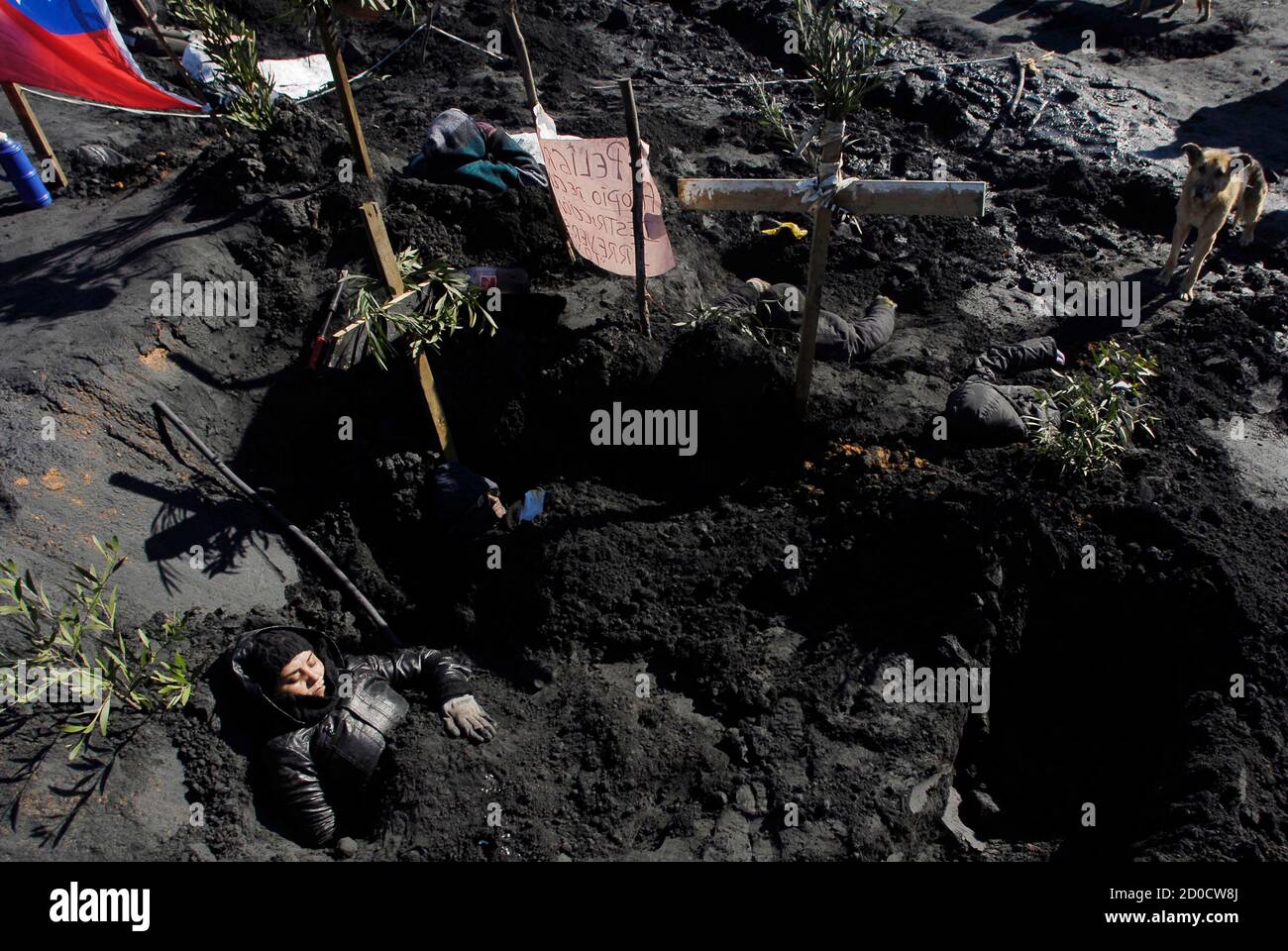 Local residents bury themselves into an ash deposit during a protest at  Coronel town south of Santiago, June 25, 2012. Locals have been protesting  against a thermo-electric plant of Spanish company Endesa