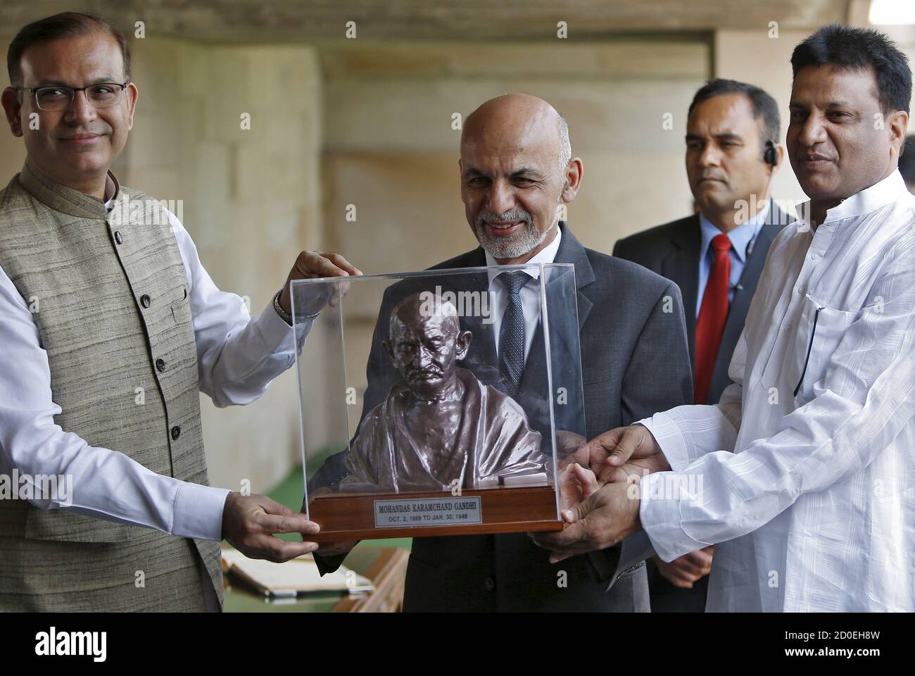 El presidente de Afganistán, Ashraf Ghani (C), recibe un busto de Mahatma Gandhi del subministro de finanzas de la India, Jayant Sinha (L), durante su visita al monumento conmemorativo de Mahatma Gandhi en Rajghat, Nueva Delhi, India, el 28 de abril de 2015. Ghani pidió el martes cooperación regional para derrotar a grupos extremistas violentos, diciendo después de reunirse con el primer ministro indio que quiere "hacer de Afganistán un cementerio de terror", pero necesita ayuda de la India, Pakistán y otros vecinos. REUTERS/Anindito Mukherjee Foto de stock