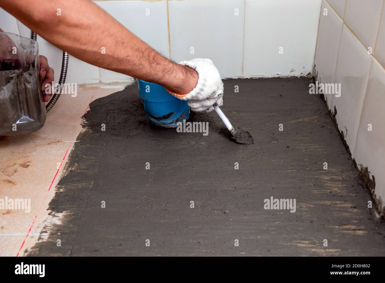 Los trabajadores de están cepillando cemento impermeabilizante en pisos de baldosas en el cuarto de baño de stock Alamy