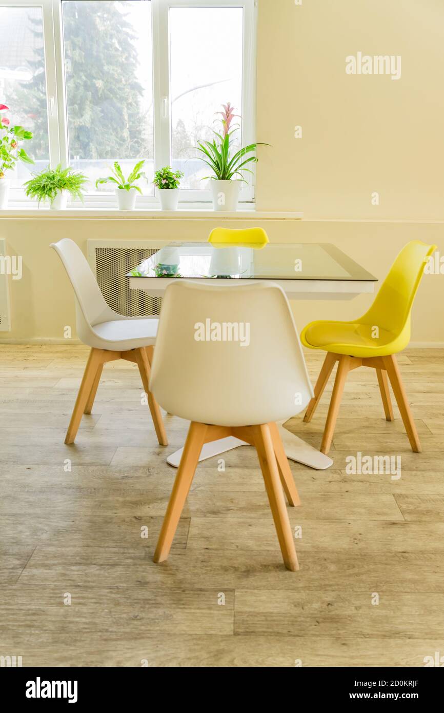 Moderno comedor diseñado en estilo scandi. Mesa de cristal y sillas  amarillas y blancas Fotografía de stock - Alamy