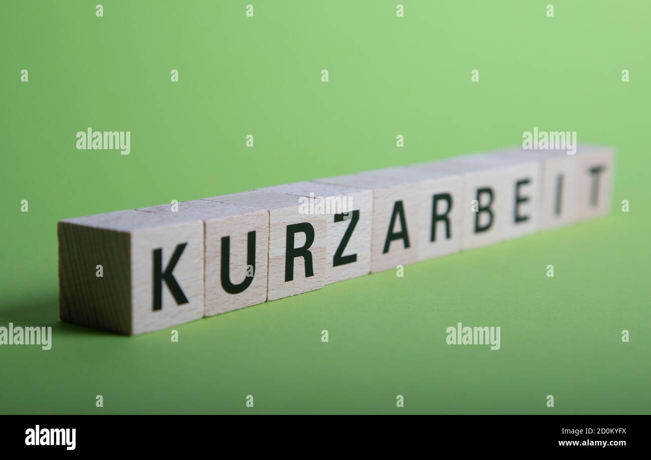 Bloques de madera con palabra alemana para trabajo de corto tiempo, Kurzarbeit, verde baclground Foto de stock