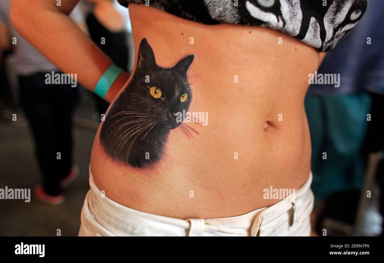 A participant shows a cat tattooed on her side during a tattoo contest at  the 4th International Tattoo Convention in Bucharest October 12, 2013.  Picture taken October 12, 2013. REUTERS/Radu Sigheti (ROMANIA -